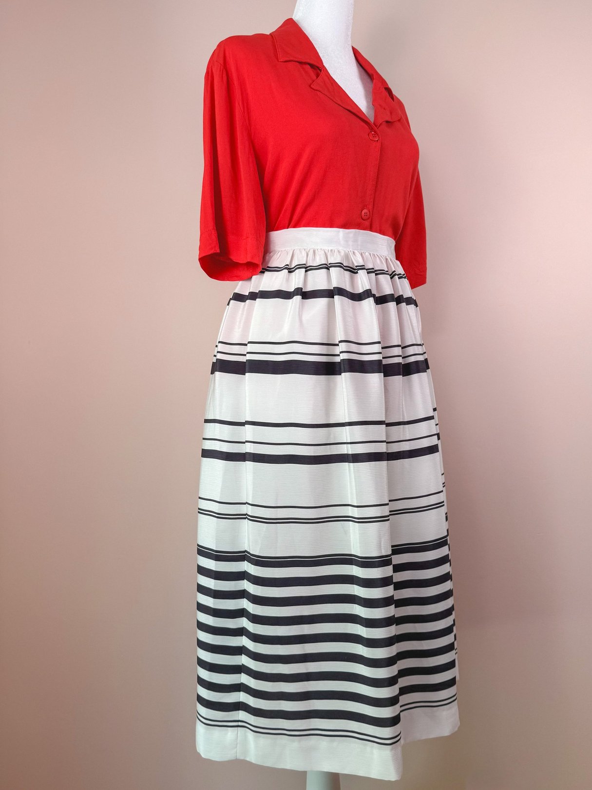 White 1970s women's skirt featuring a horizontal black stripe pattern and a cinched waistband, styled with a red short-sleeve top.