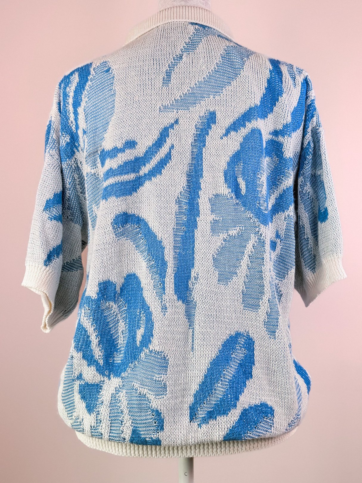 White Yasaki Knit Polo Sweater with blue floral pattern, featuring short sleeves and a collared neckline, from the 1980s.