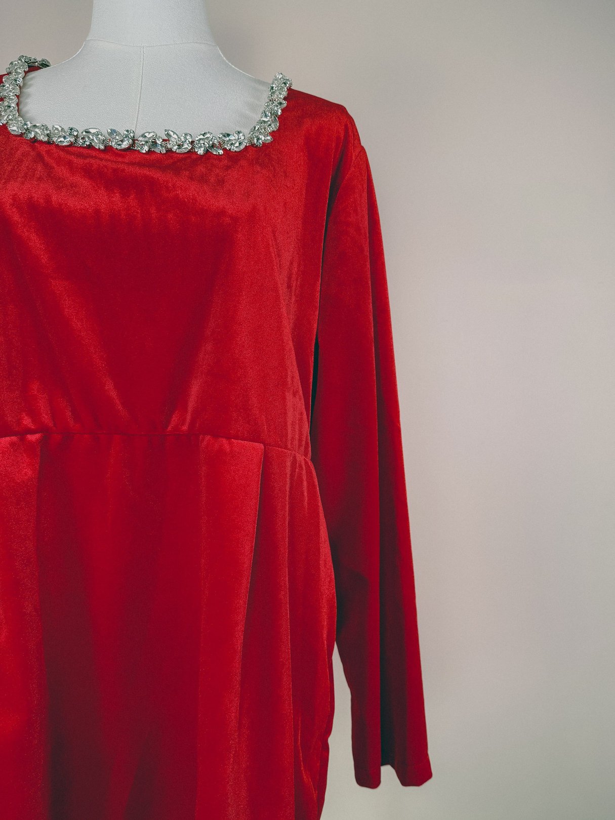 Red velvet dress with long sleeves and a jewel-encrusted neckline, designed for women, from the 1970s.