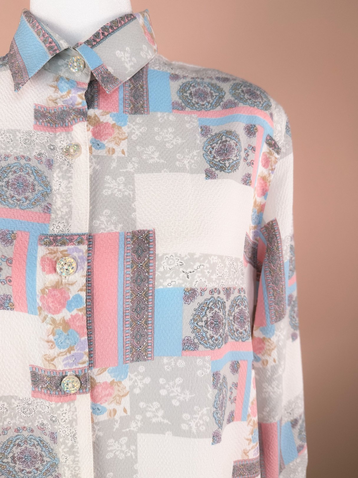 White 1980s patchwork medley blouse featuring floral and geometric patterns with buttons at the collar.
