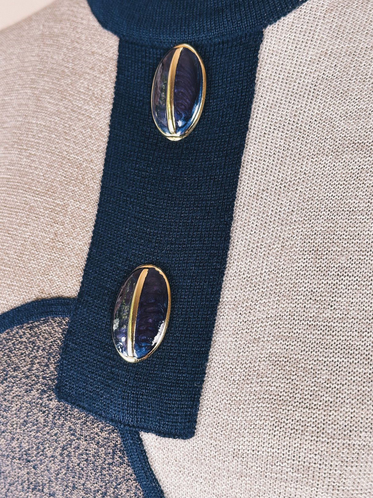 Navy blue sweater dress featuring two decorative gold and navy buttons at the neckline, styled in a retro 1980s design.