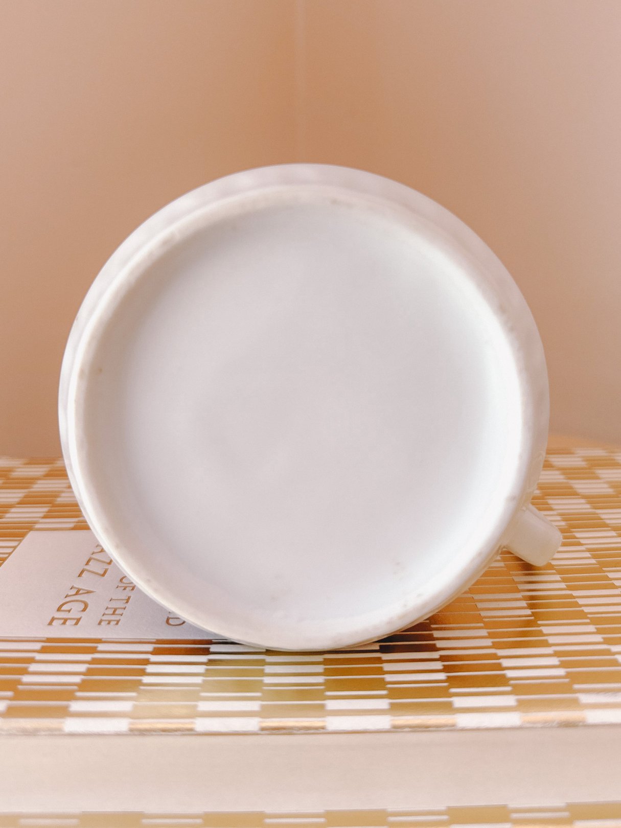 A white mug featuring a houndstooth print design, set against a patterned surface.