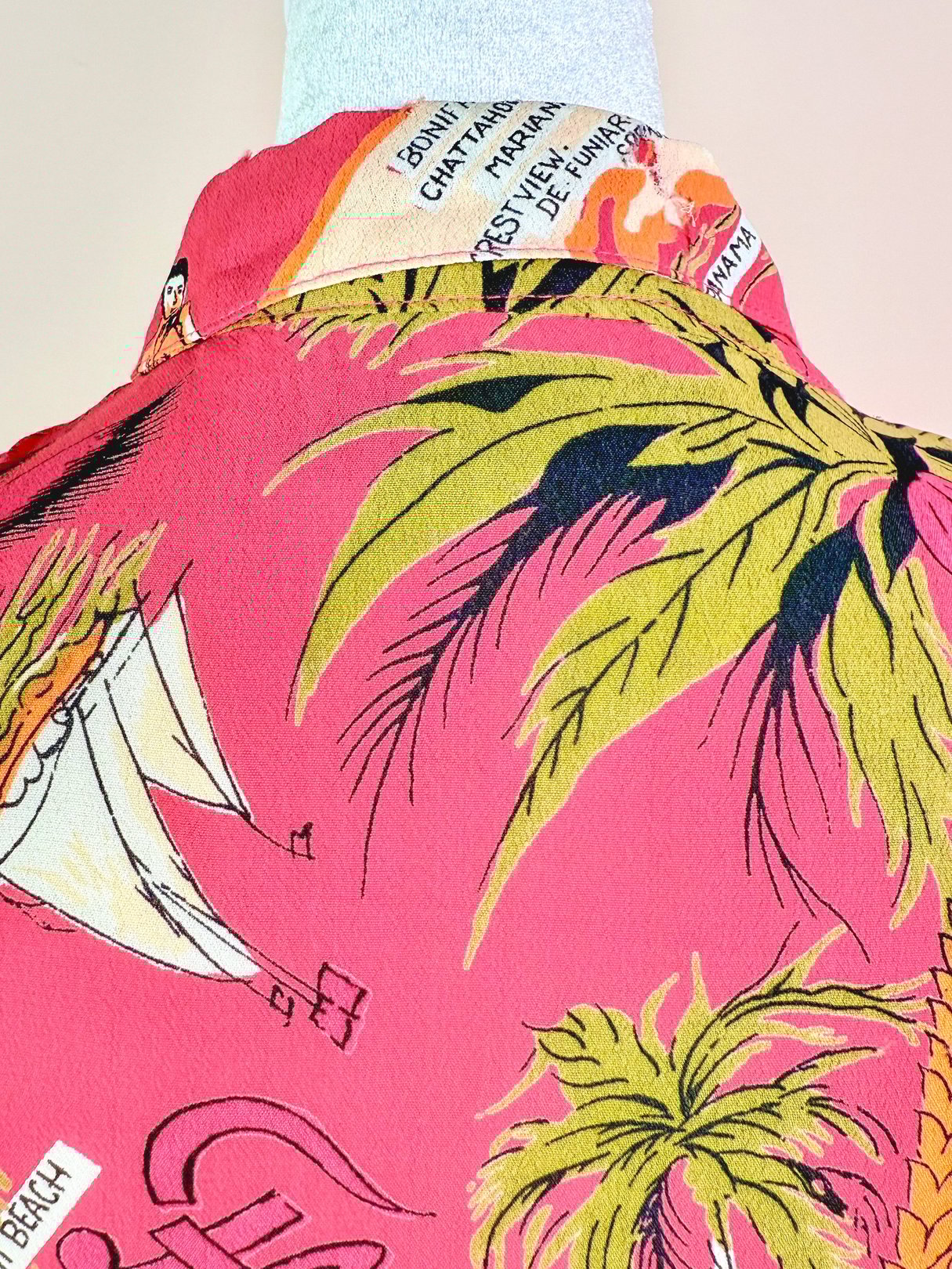 White women's top from the 1970s featuring a colorful tropical design with palm trees and beach imagery.