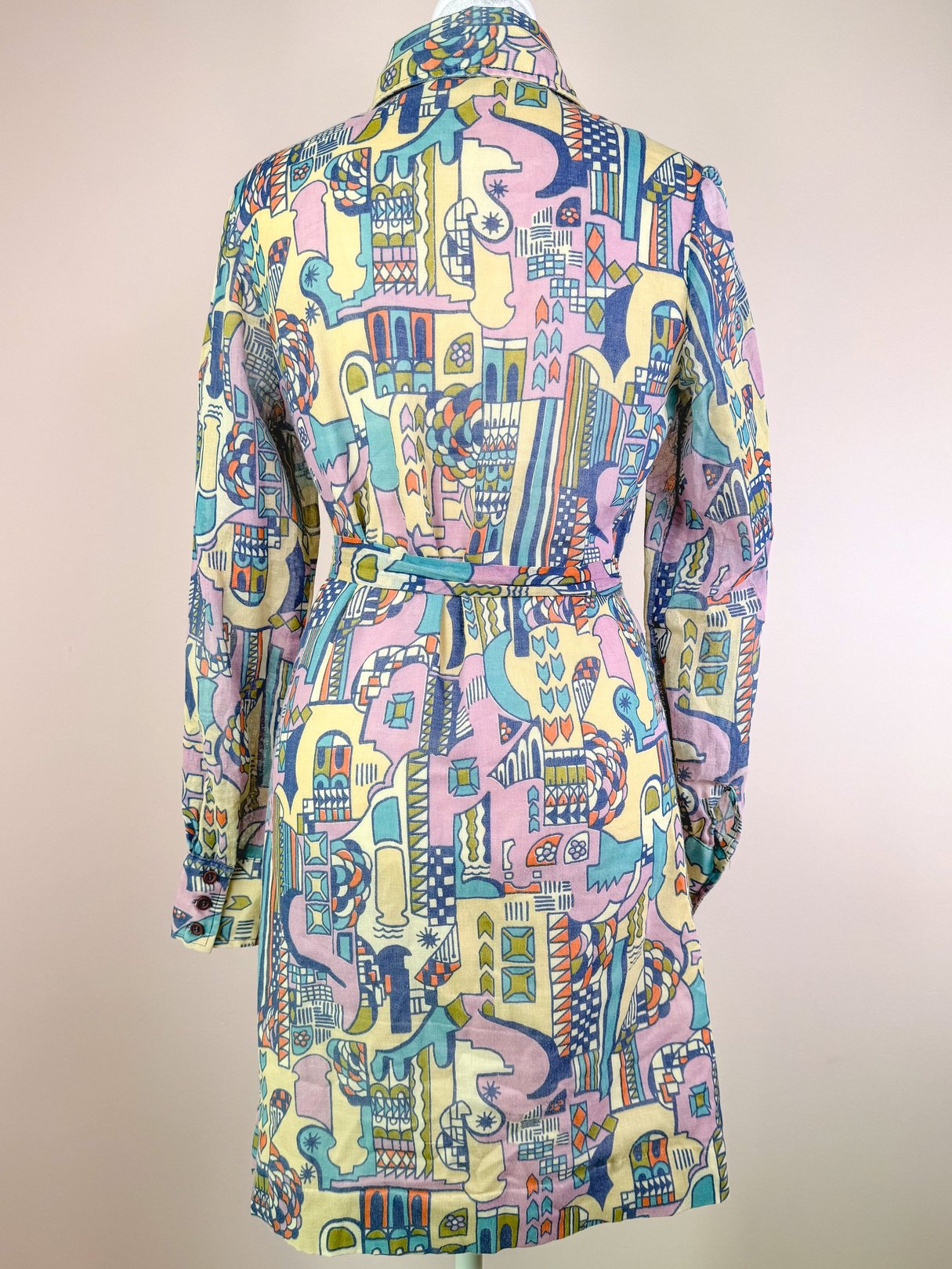1970s cream dress featuring colorful abstract patterns and a belted waist.