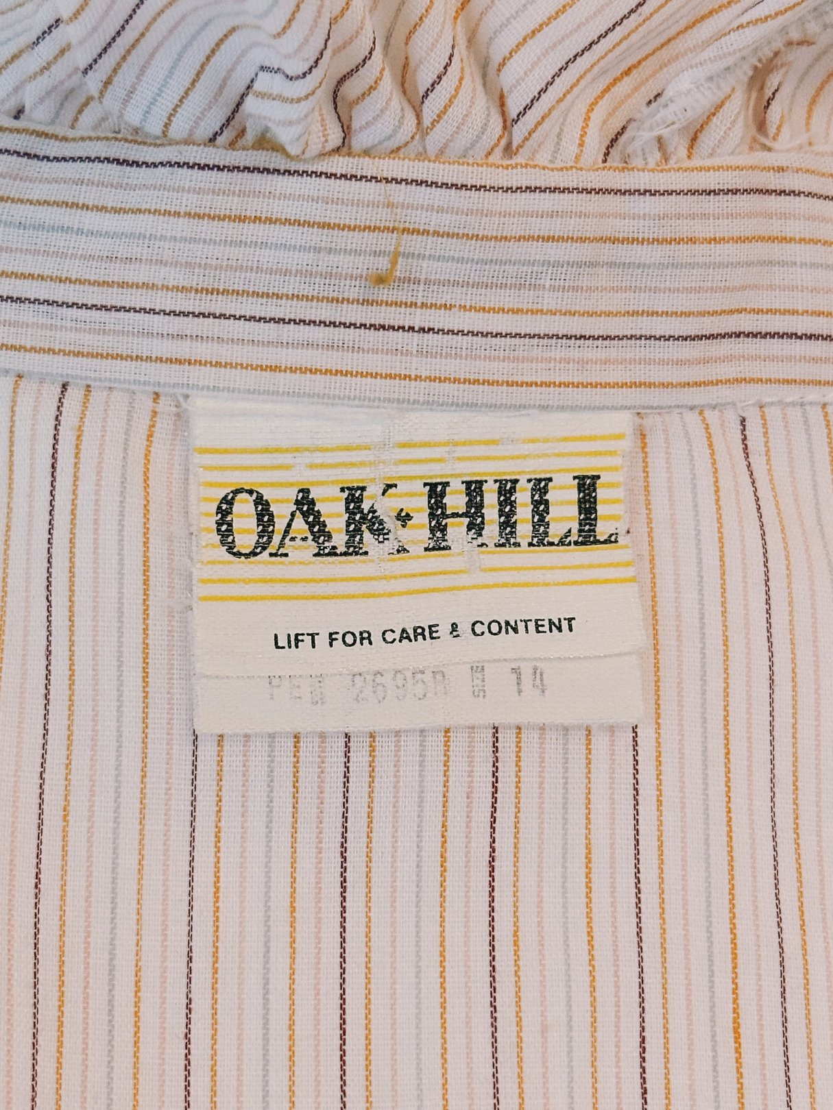 Cream blouse with ruffled neck featuring intricate pink, orange, and blue stripes, made by Oak Hill, reflective of 1970s fashion.