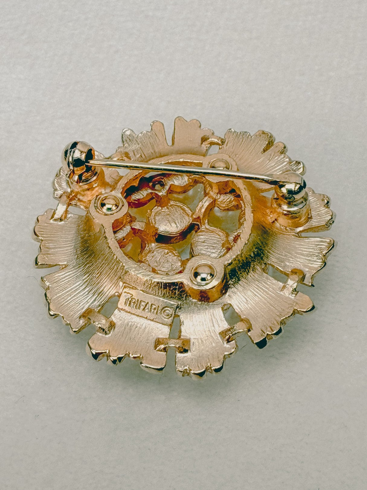 Gold-tone costume jewelry brooch from the 1970s featuring a floral design with a pin back.