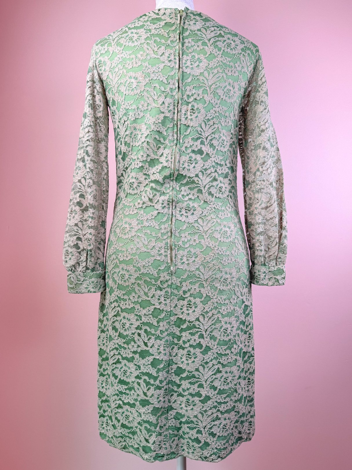 Seafoam green 1960s women's dress featuring intricate lace detailing and long sleeves, displayed from the back.