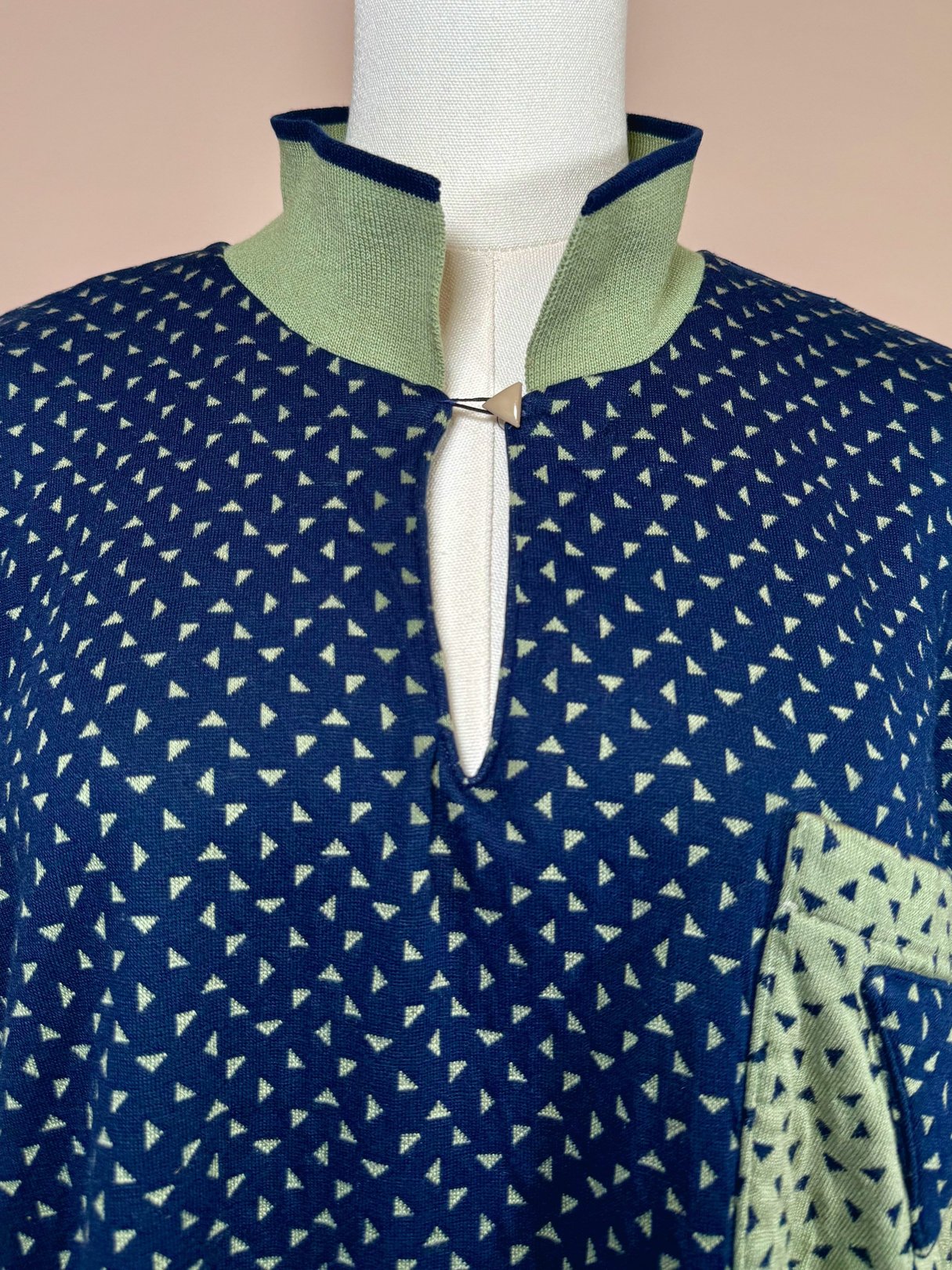 Navy blue women's triangle top from the 1980s featuring a half zipper and a geometric print with green accents.