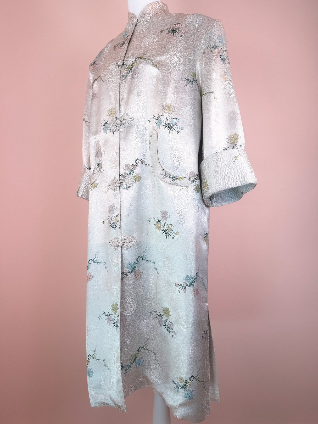 Silver 1970s women’s Harmony Silk Cheongsam Coat featuring floral patterns and cuffed sleeves.