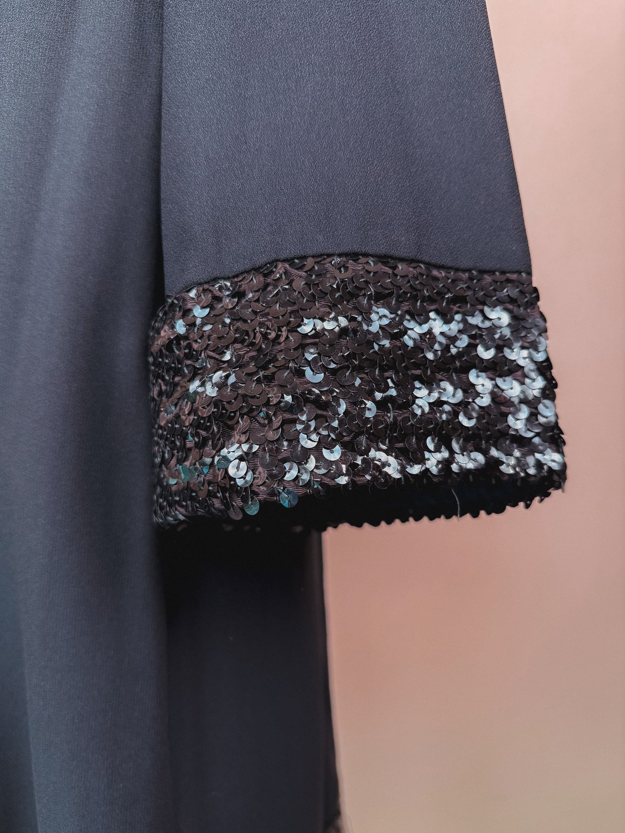 Black 1960s women's dress featuring sequined cuffs.