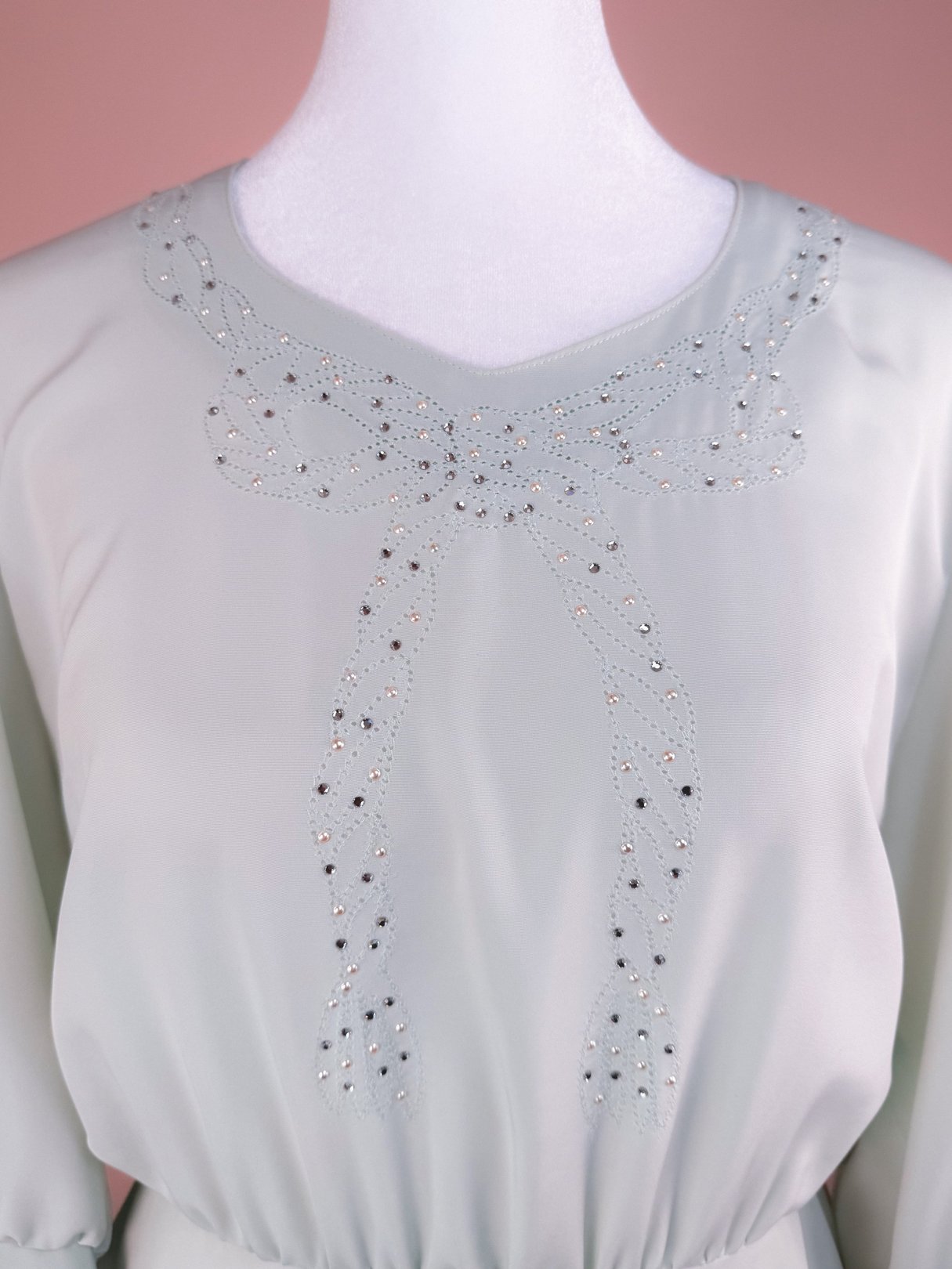 Mint green 1980s women's dress featuring a sparkling decorative bow design on the bodice.