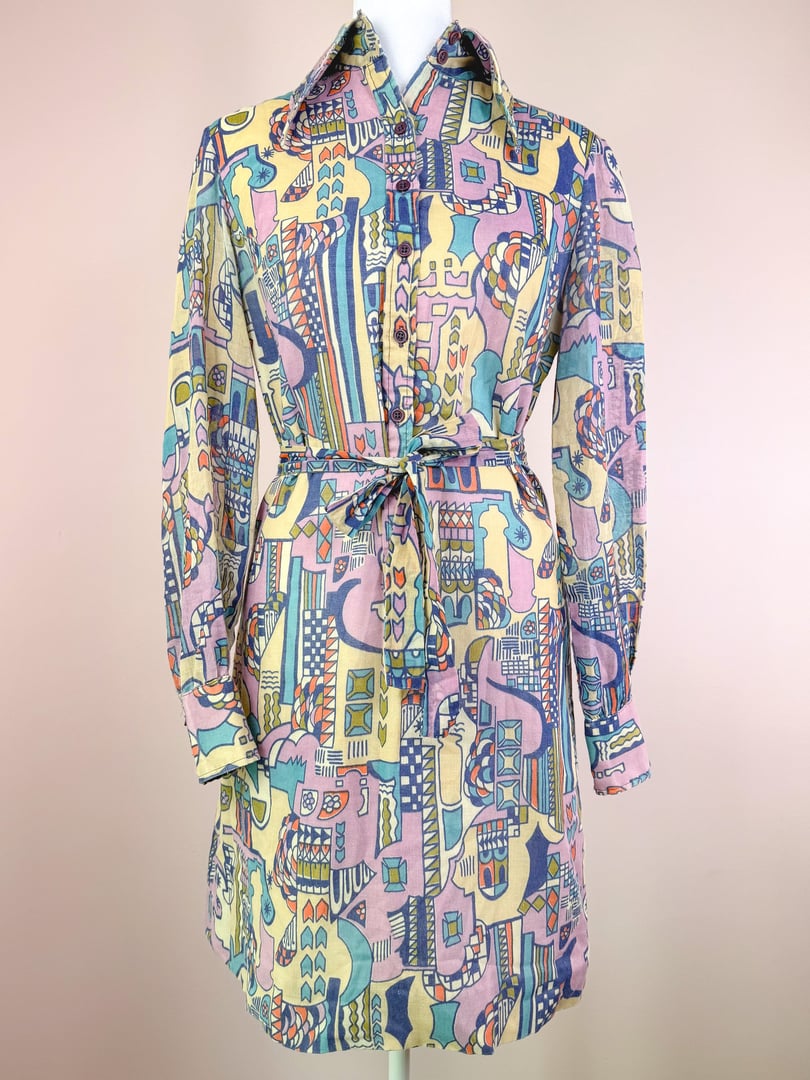 Cream-colored 1970s Metropolis dress featuring a colorful abstract print and a belted waist.