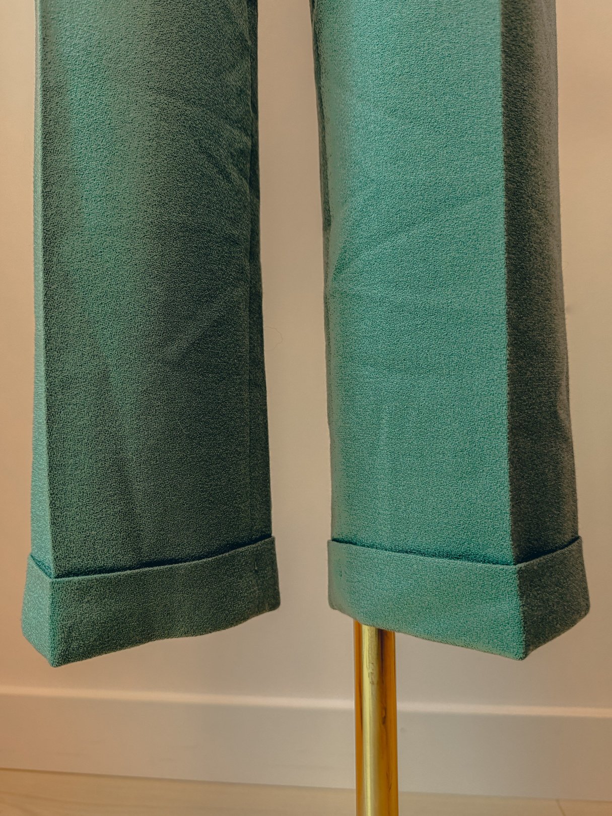 Sage green pleated trousers with a tailored fit and rolled cuffs, styled for women in the 1980s.