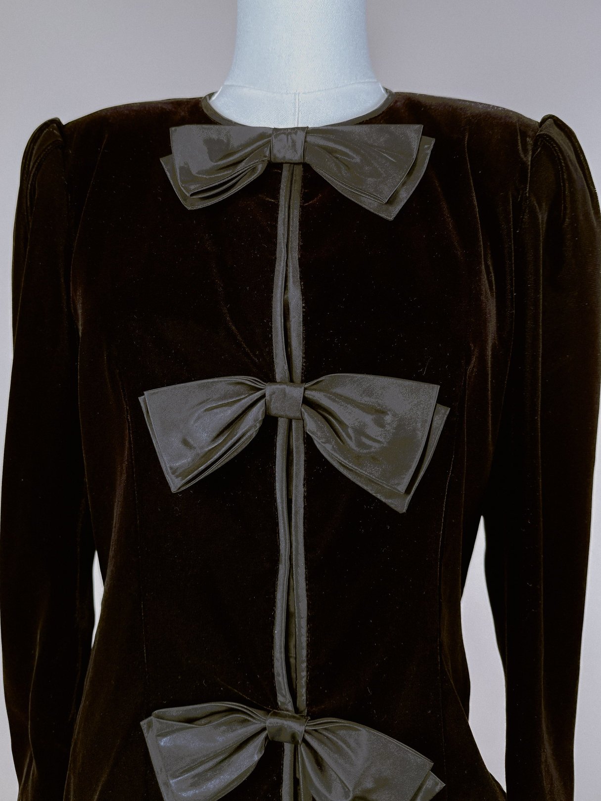 Black velvet jacket for women featuring a front bow detail, reflective of 1980s fashion.
