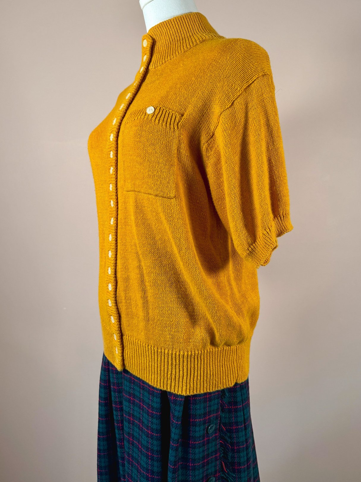 A vintage 1980s women's sweater in persimmon orange with short sleeves and a front button closure.