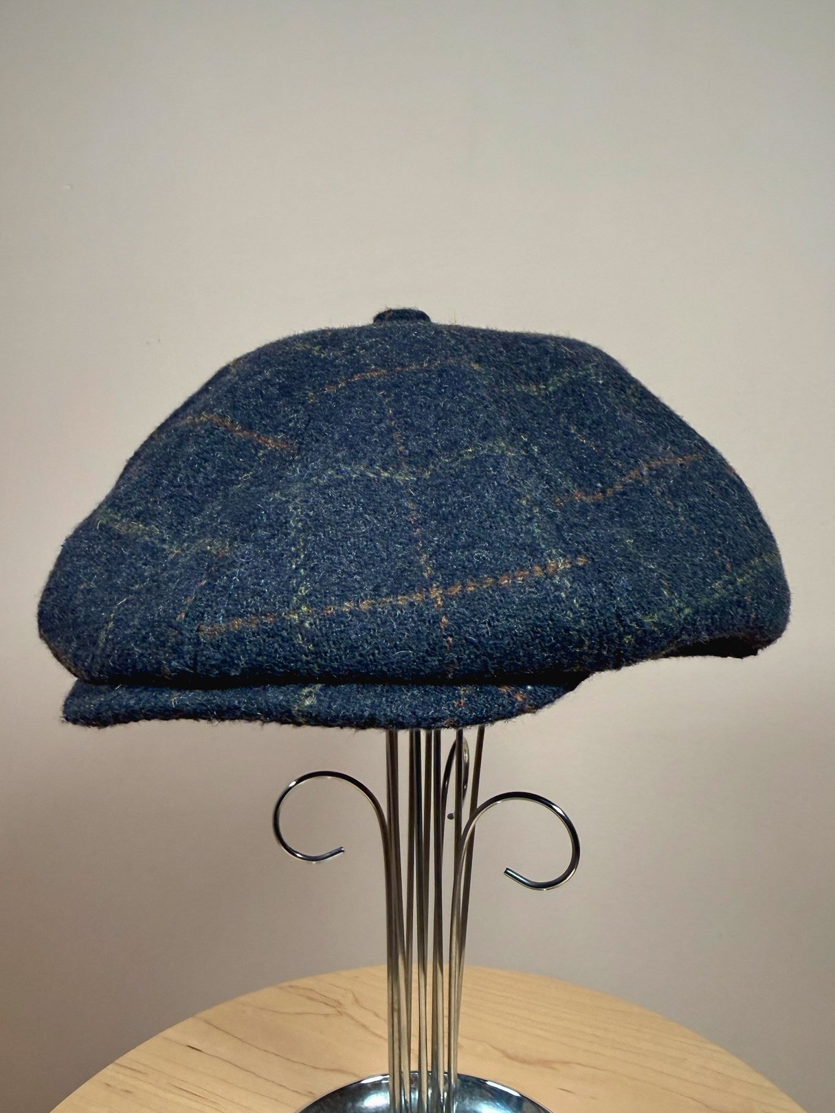 Navy blue tweed cap with a plaid pattern, designed for men, reflecting a 1970s style.