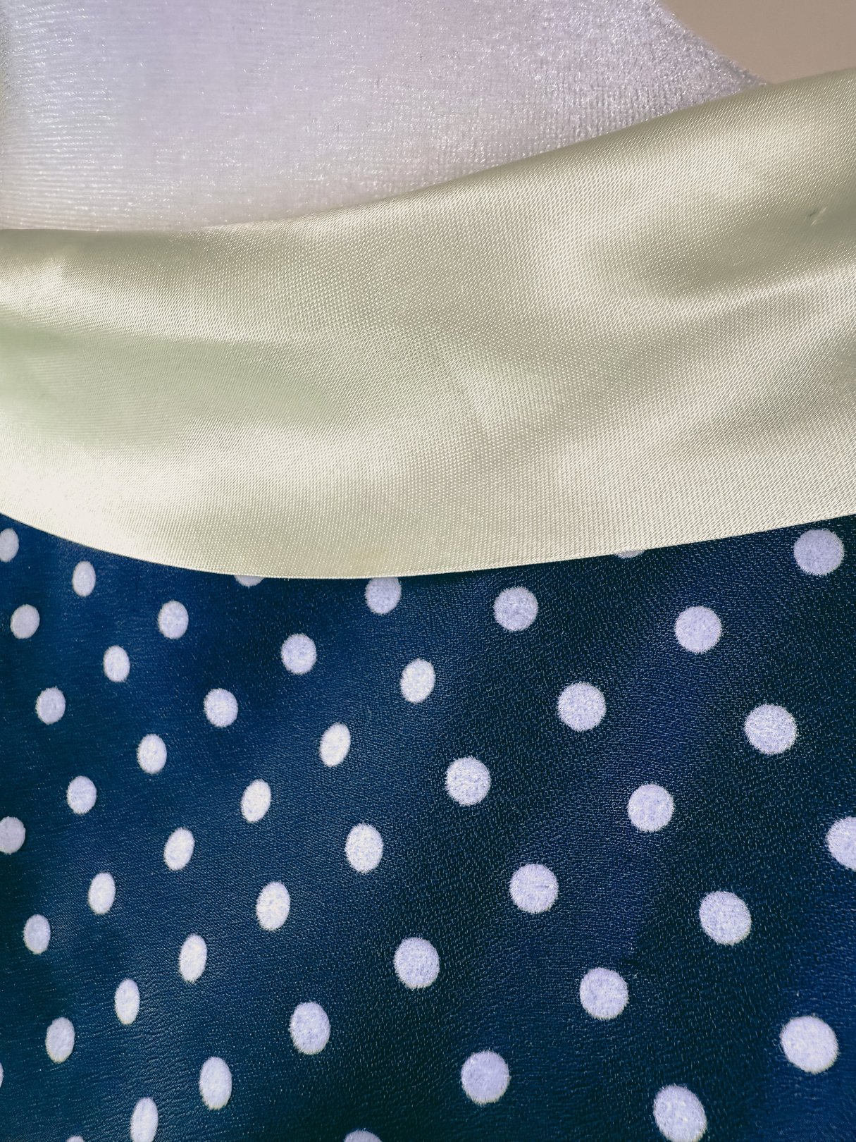 Navy blue dress with white polka dots and a light green collar, reflecting a 1950s style.