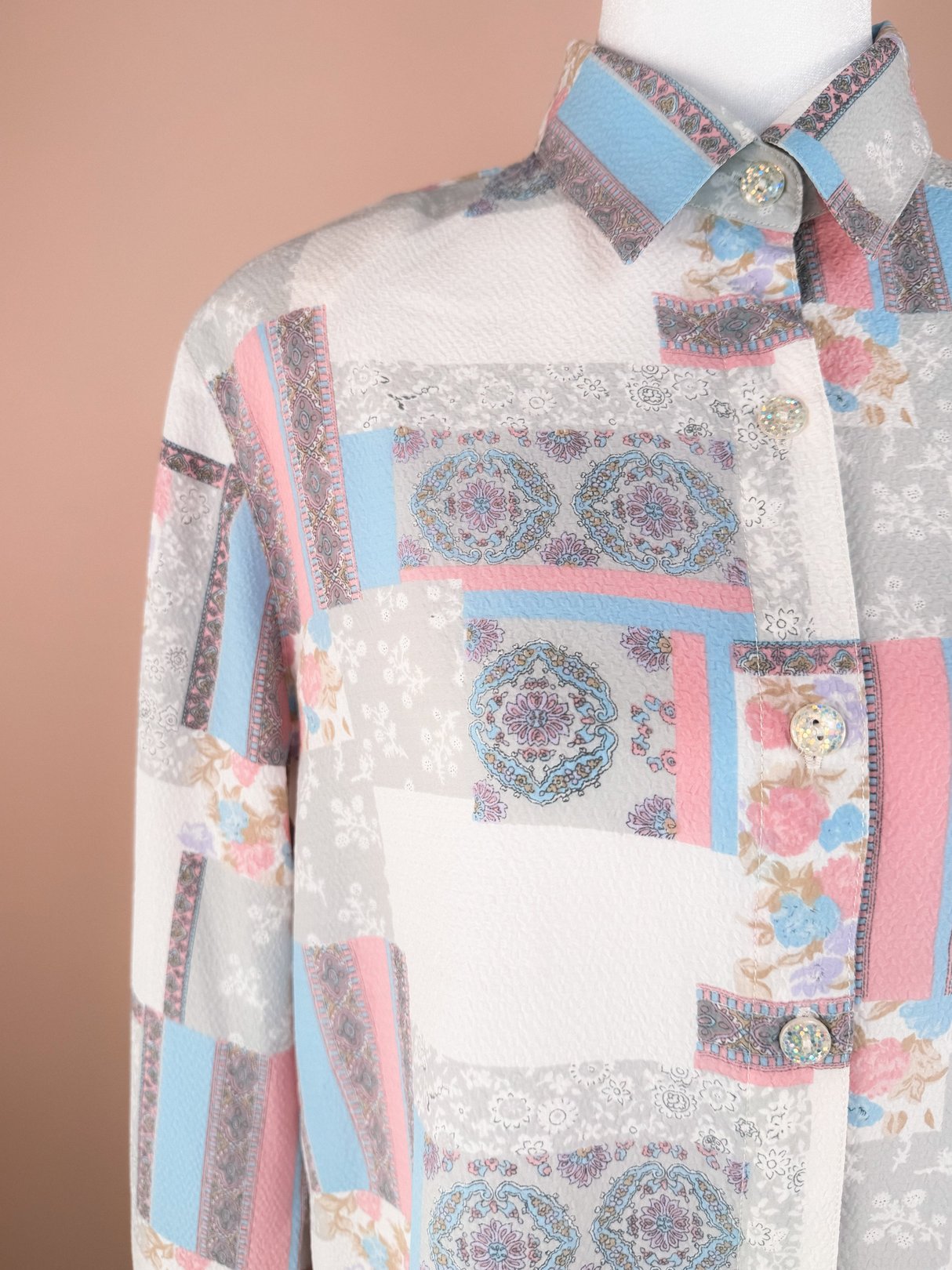 Women's 1980s Patchwork Medley Blouse in white featuring a colorful patchwork design with floral and geometric patterns, button-up front, and collar.