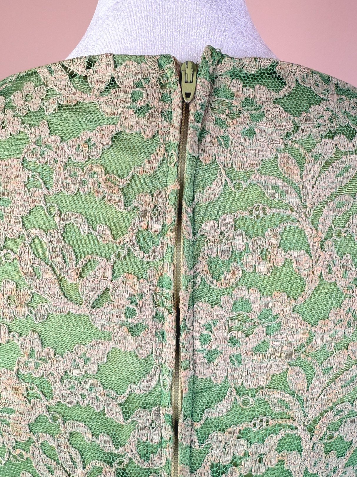 Back view of a 1960s women's dress in seafoam green lace featuring a zipper closure.