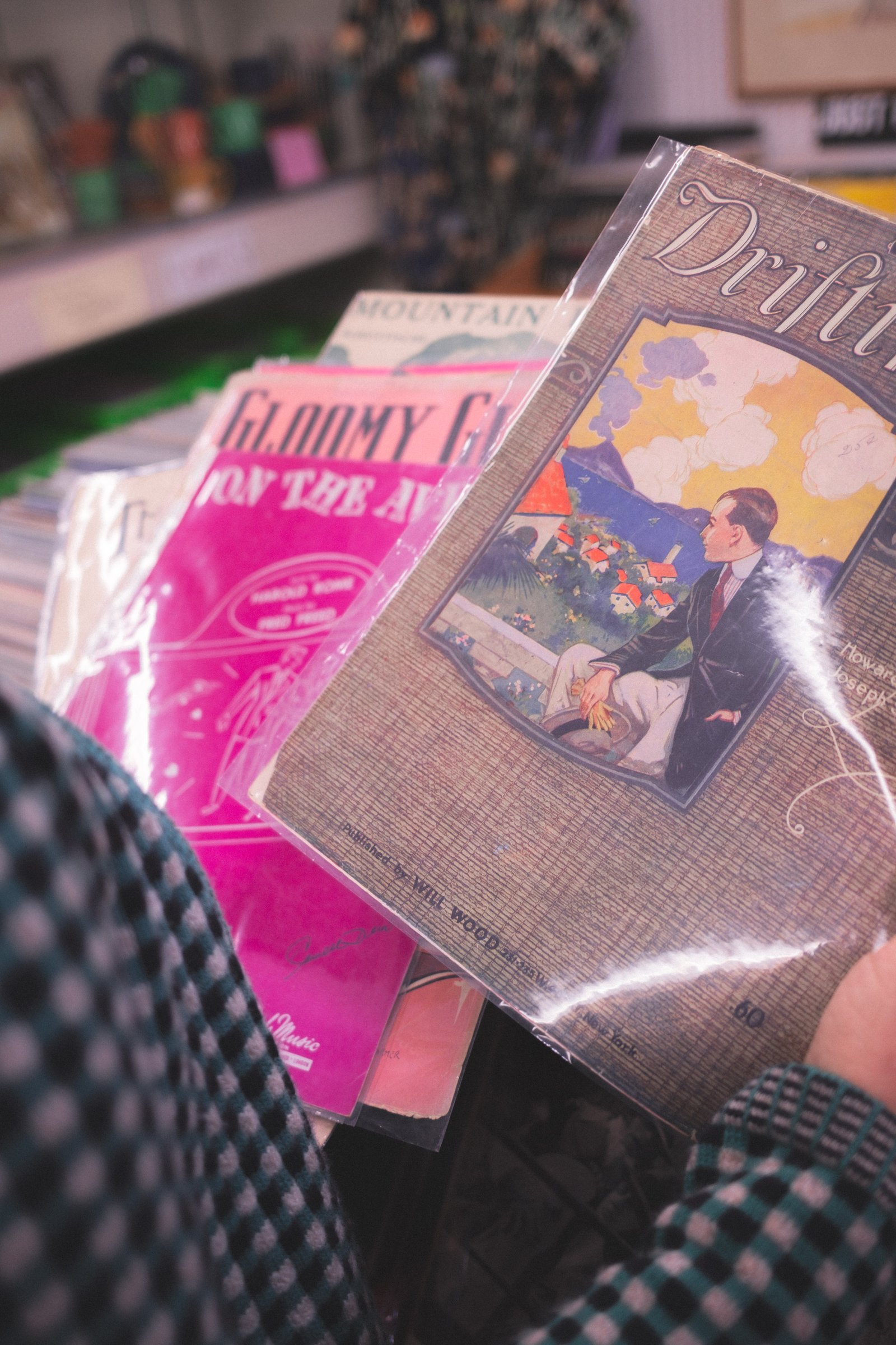 Sheet Music Stories gallery image: A collection of vintage sheet music covers featuring colorful illustrations and typography, with prominent titles visible in pink and gold hues.