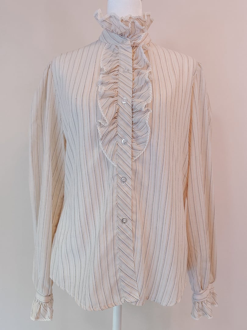 Cream blouse featuring a ruffled neck and intricate pink, orange, and blue stripes, with long sleeves and button closure.