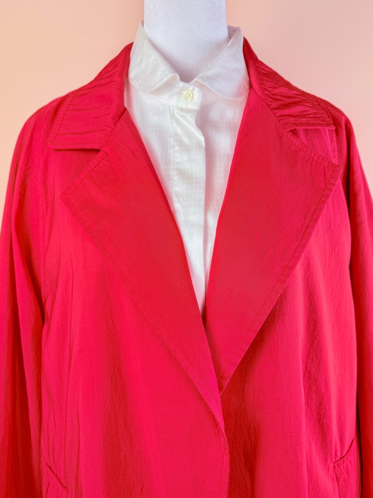 Red women's 1980s Poppy Forecast rain jacket with a large collar, displayed over a white button-up shirt.