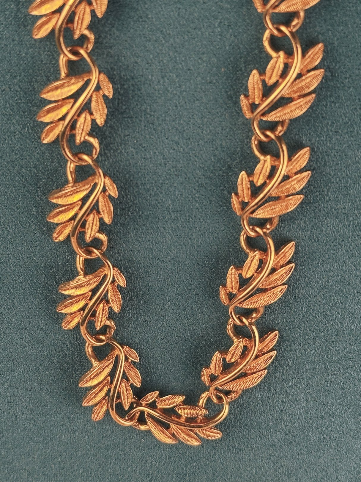 Gold-tone collar necklace featuring a swirled vine design, reflective of 1970s style.
