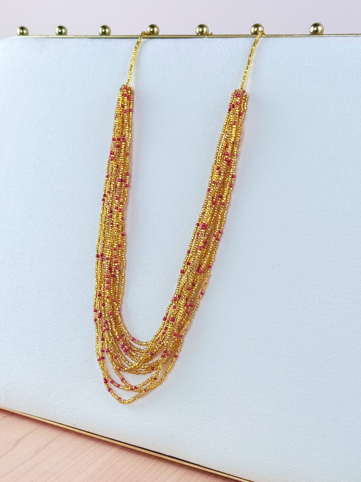 A multi-strand marigold necklace featuring shimmering gold and pink beads, reflecting a 1990s jewelry style for women.