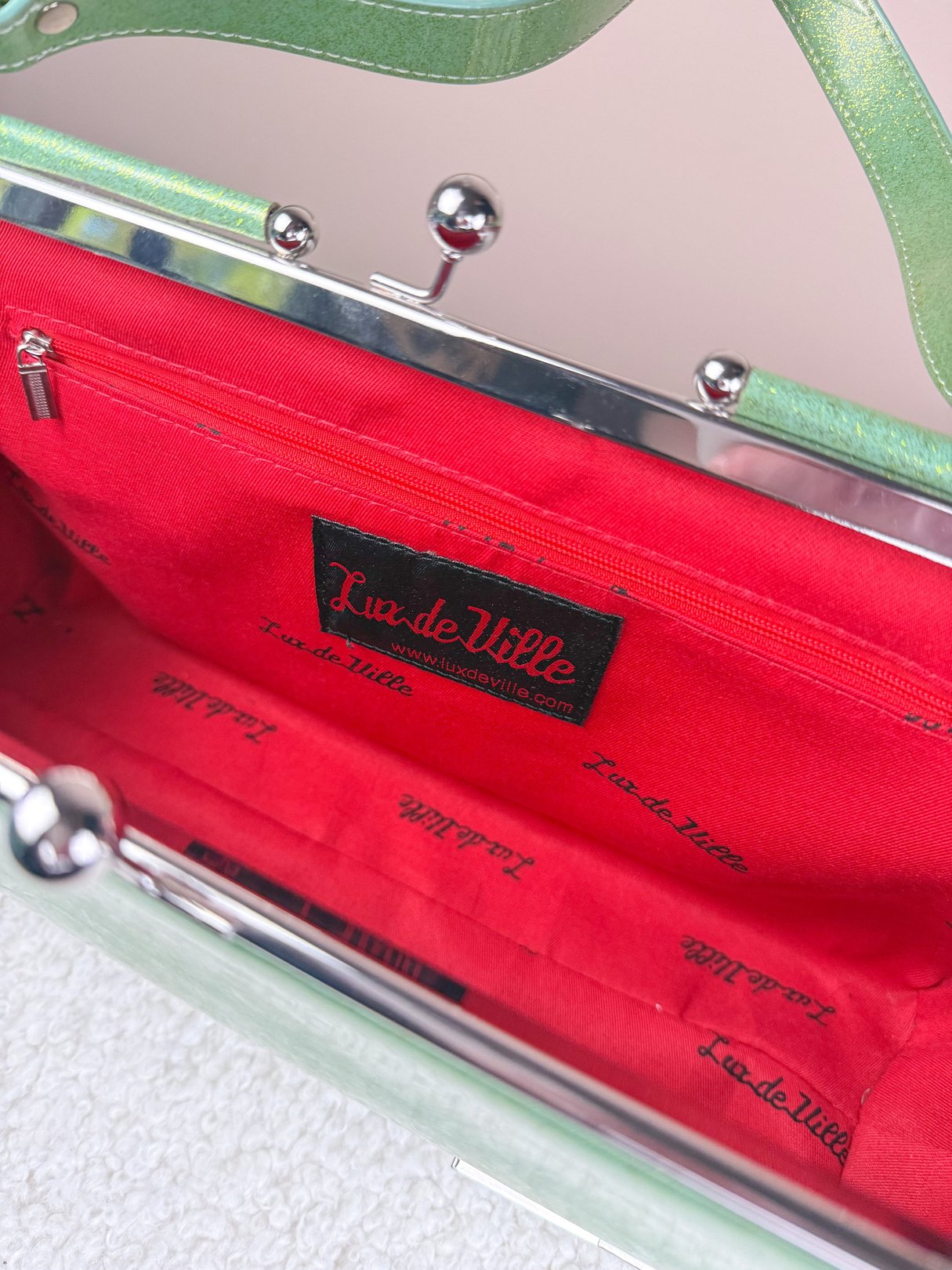 Sparkling mint green 1950s women's handbag with a red interior featuring the Lux de Ville logo.