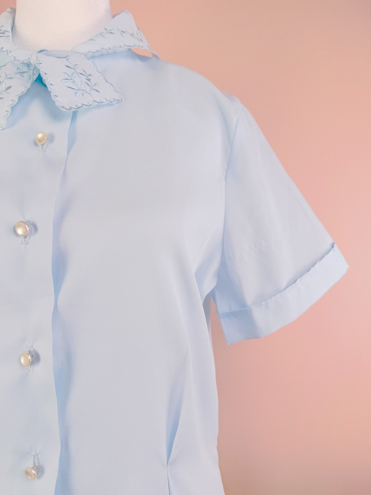 Powder blue blouse for women from the 1950s featuring a collar with embroidery and front pearl buttons.