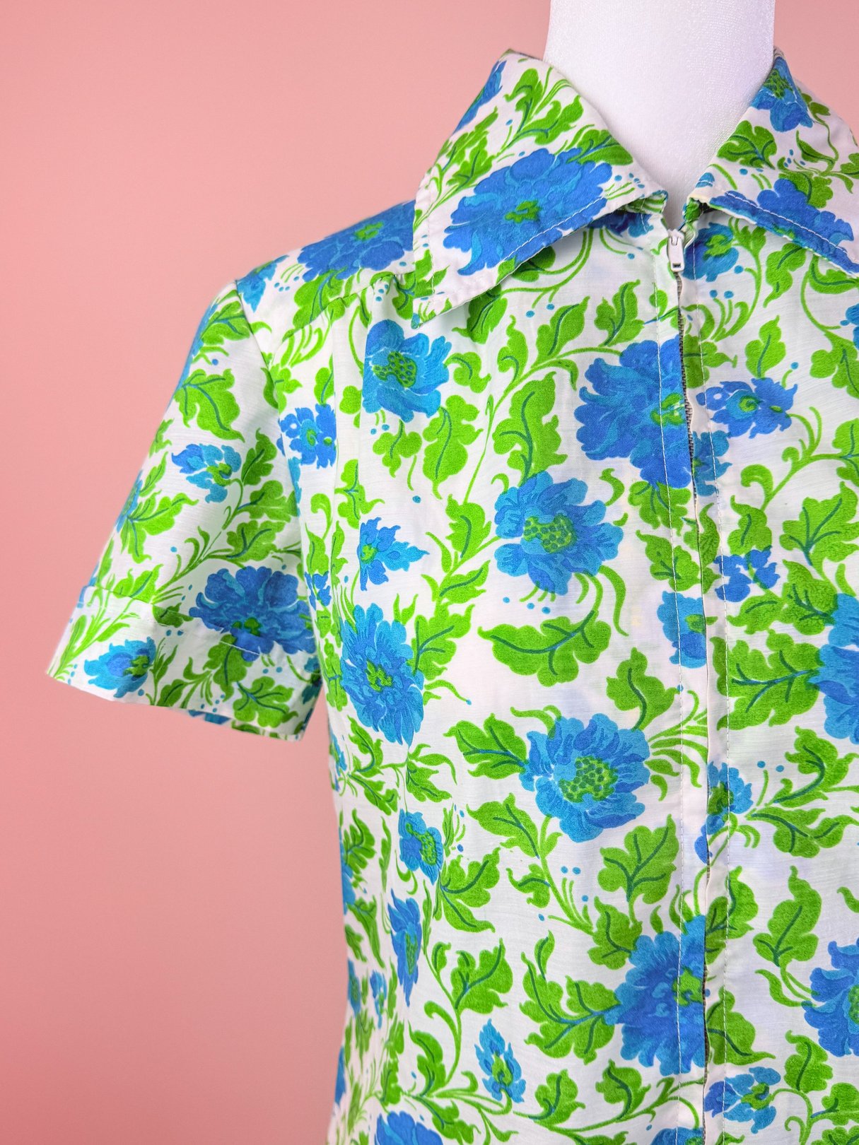 Short-sleeved white dress featuring a vibrant blue and green floral pattern, styled in a 1960s design.