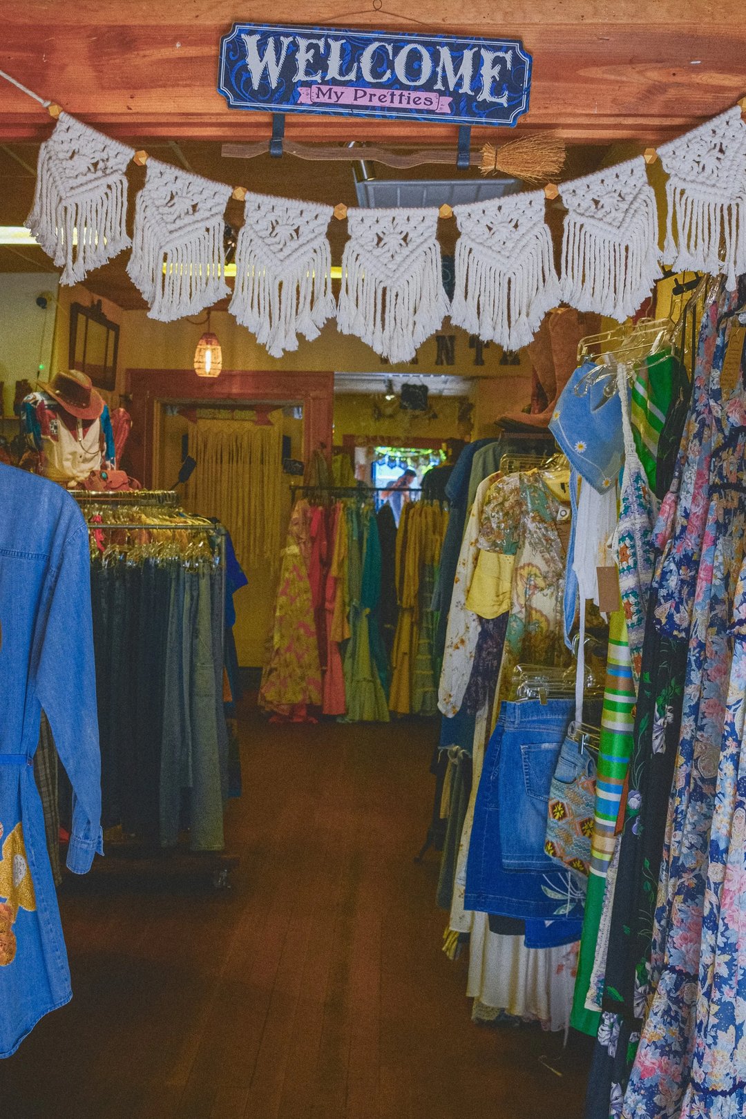 A vibrant boutique interior featuring racks of colorful clothing and decorative bunting.