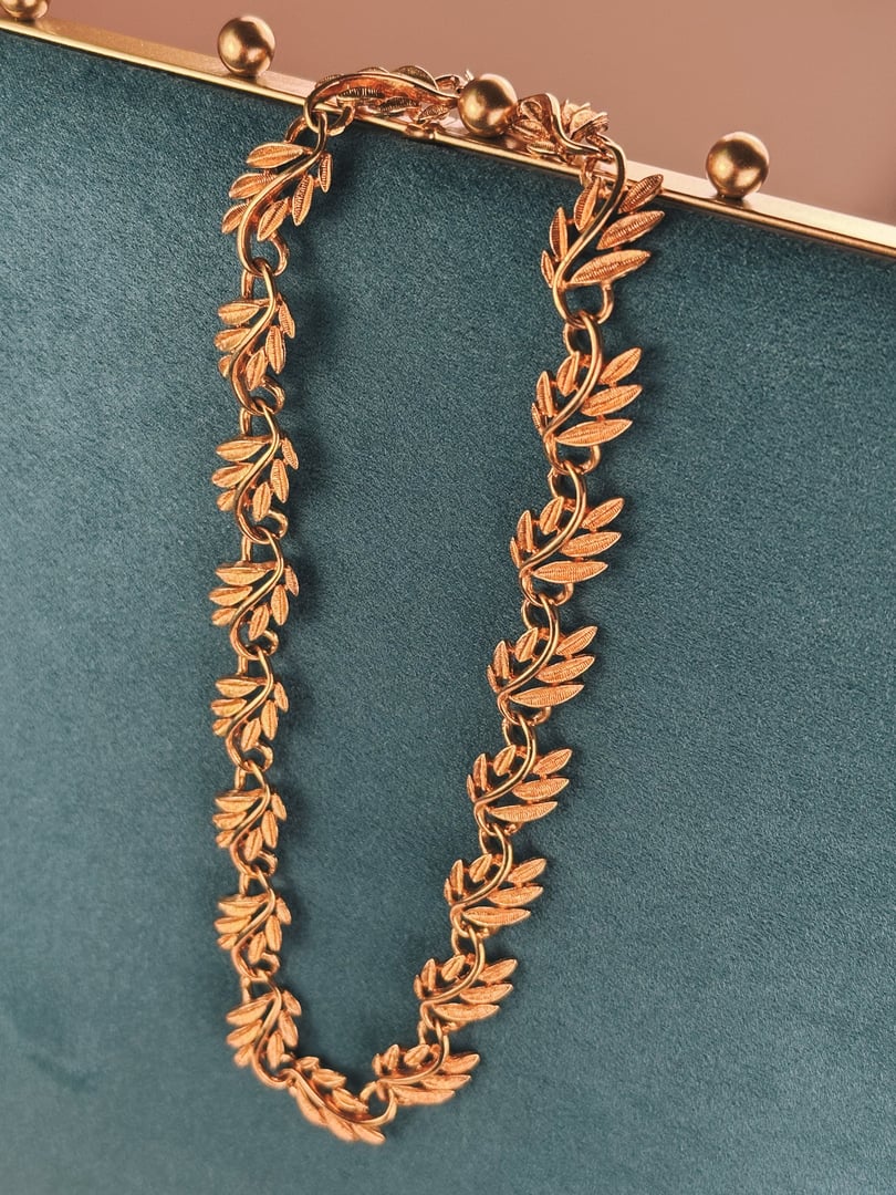 Gold tone collar necklace featuring a swirled vine design, designed for women, from the 1970s.