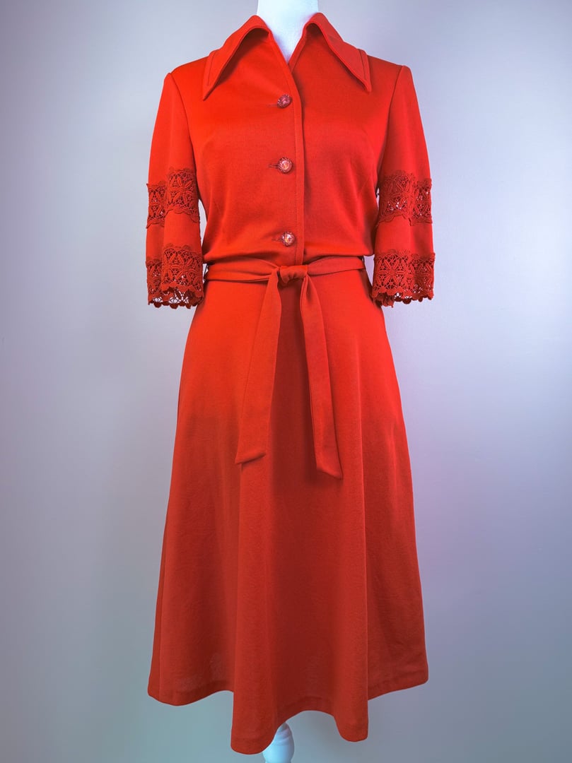 1970s women's cherry red lace bell dress featuring a collared neckline, three-quarter sleeves with lace accents, and a cinched waist with a matching belt.