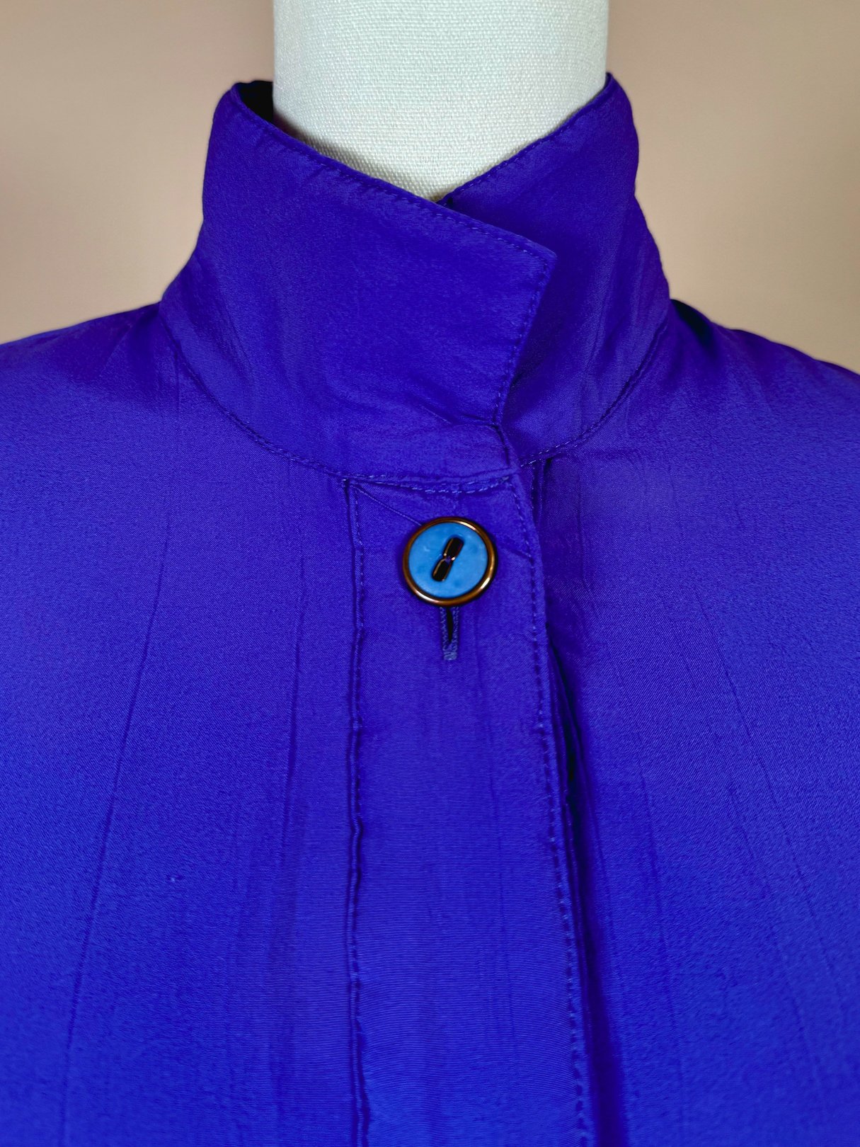 Vibrant violet women's 1980s jacket featuring a high collar and a blue button closure.