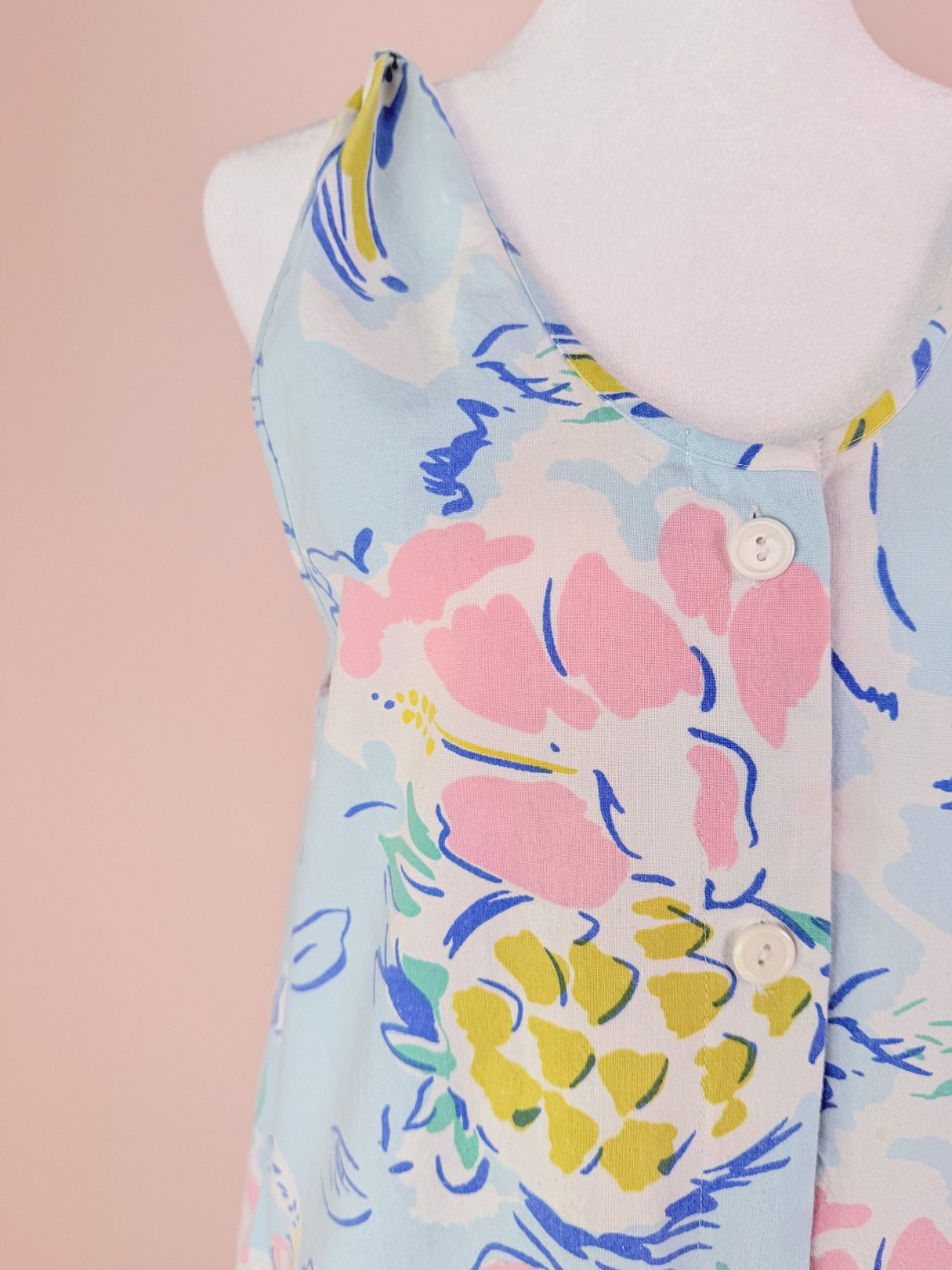 Light blue women's romper featuring a floral pattern with pink, yellow, and green accents, styled with buttons on the front.