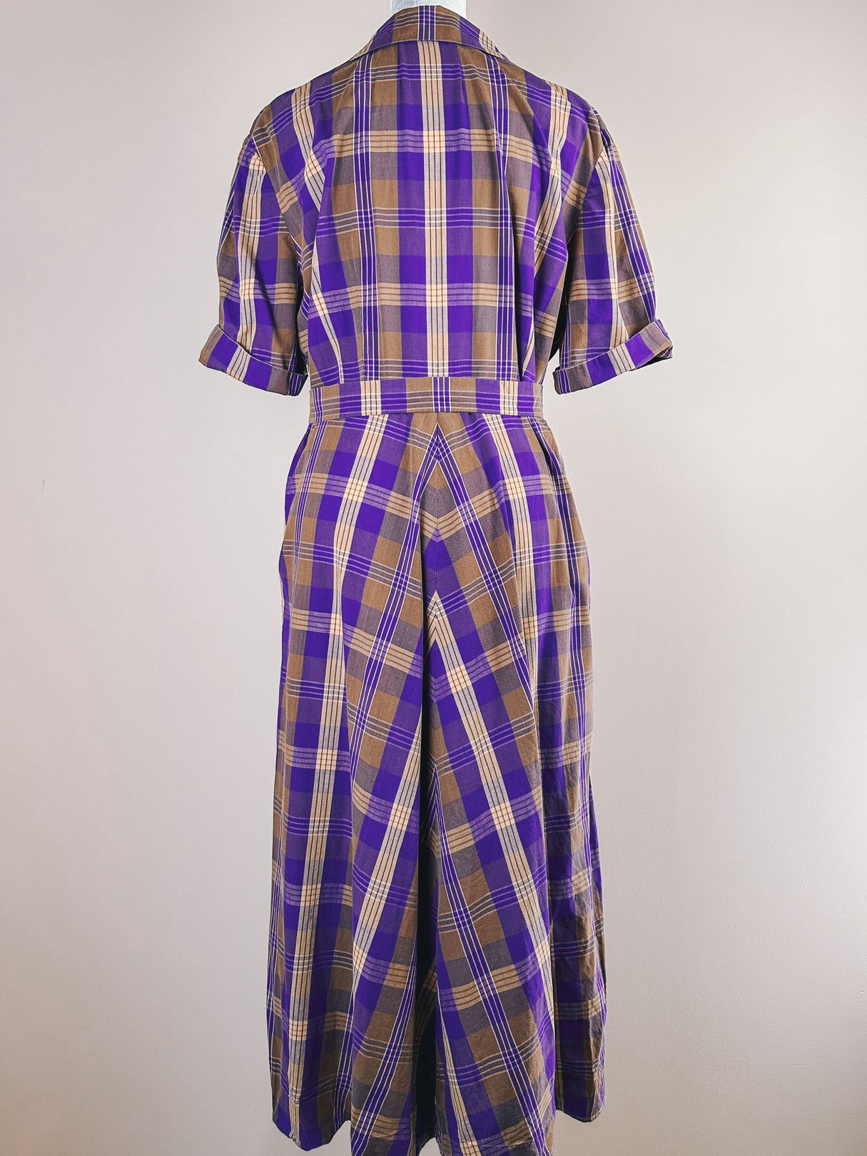 Back view of a women's 1950s purple plaid retreat dress featuring short sleeves and a cinched waist.