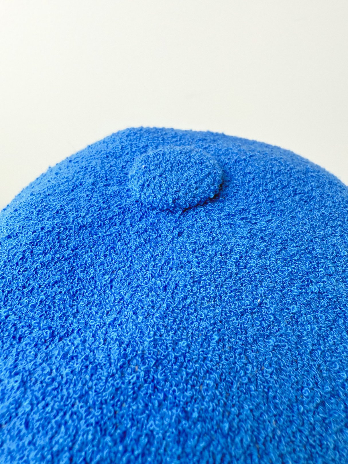 Cobalt blue bucket hat featuring a textured fabric and a button on top.