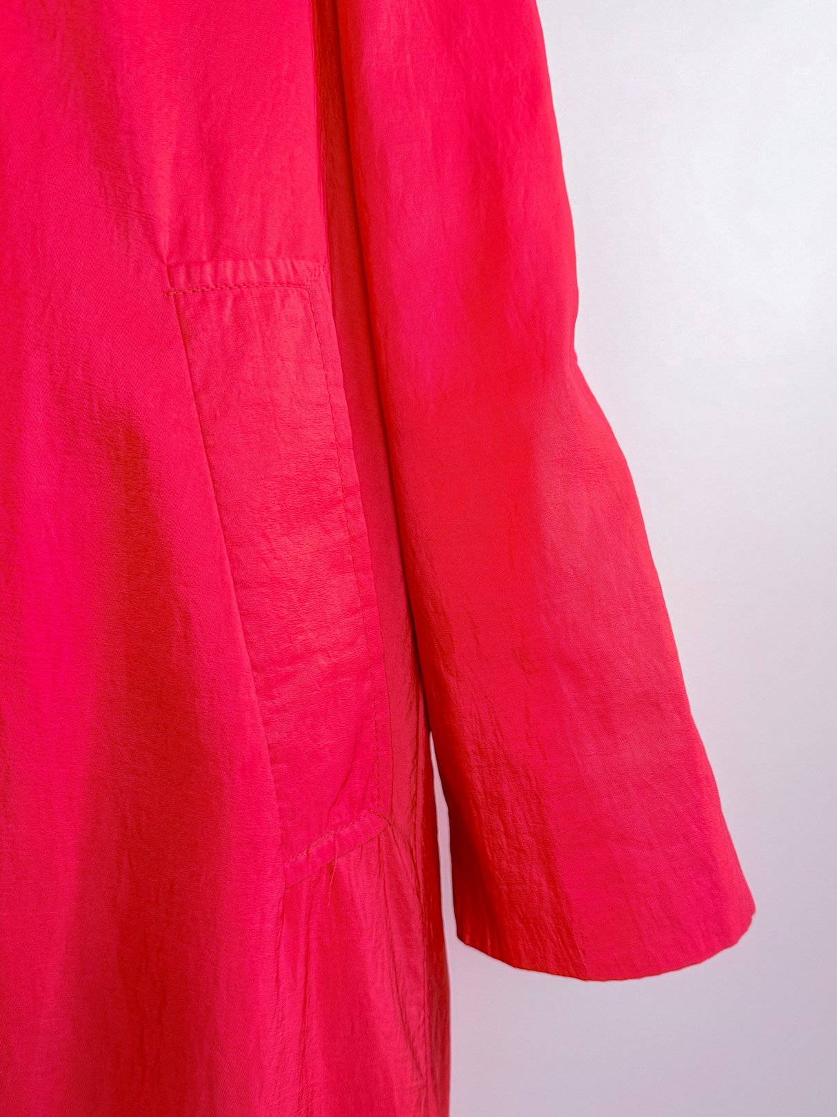 Red 1980s women's rain jacket with a pocket and a long sleeve.