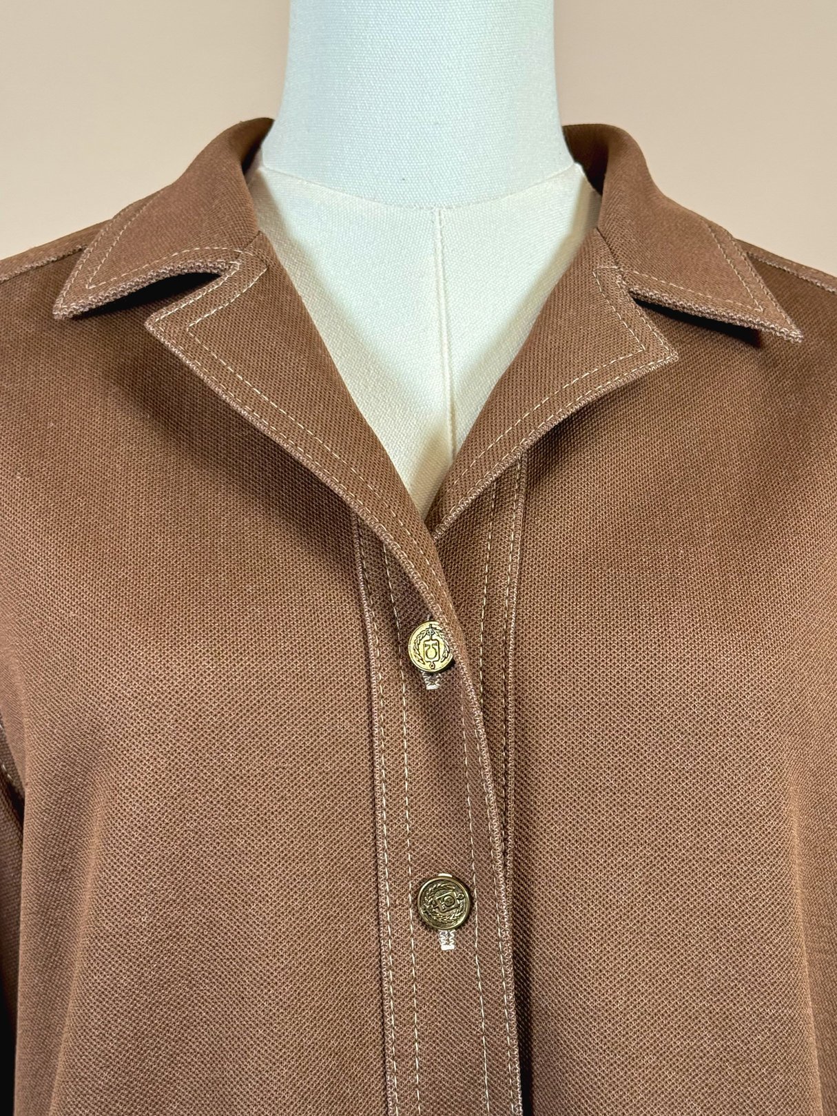 Brown 1960s women's jacket featuring a collared neckline and two gold-tone buttons.