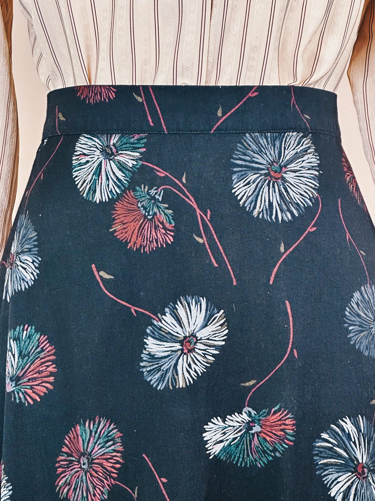 Black skirt with a floral dandelion print, featuring a ruffled hem, styled for women in a 1970s fashion.