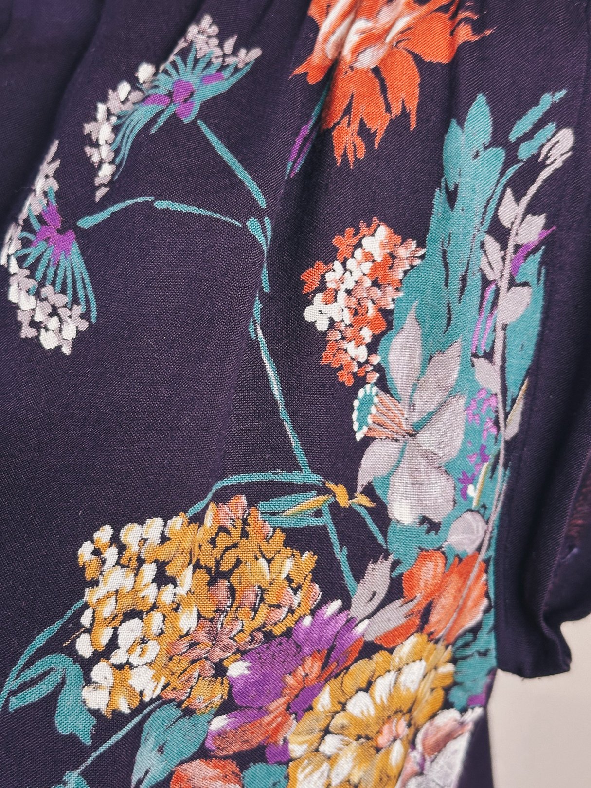 Purple dress with a floral print featuring bright colors, inspired by 1970s fashion, designed for women.