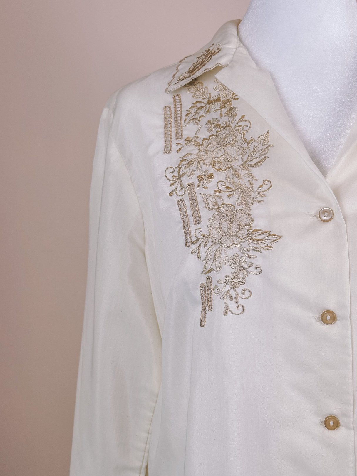 Cream 1950s women's hand-embroidered scalloped button-down blouse featuring floral designs along the neckline.
