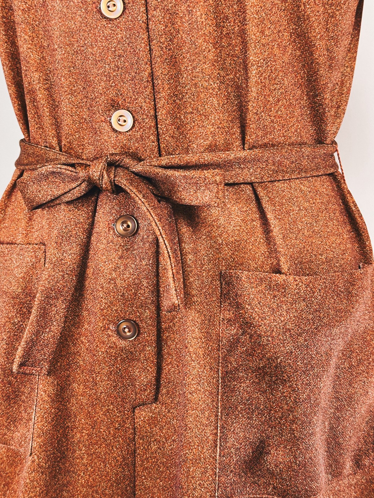 Brown 1970s-style women's day dress featuring a belted waist, button closures, and front pockets.