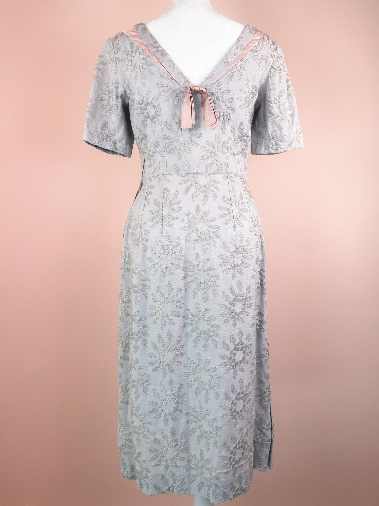 Slate blue 1950s women's dress featuring floral embroidery and a bow detail at the neckline.