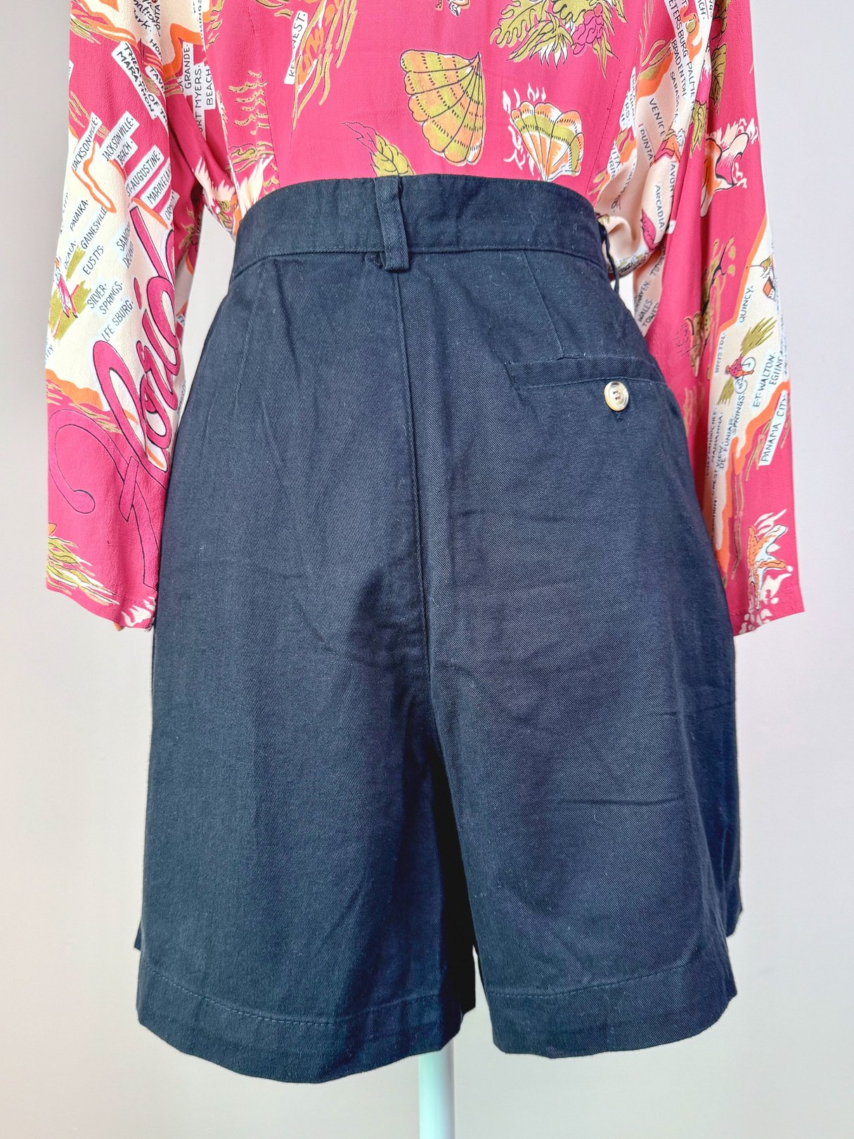 Black women's shorts from the 1980s featuring a front pocket and single button detail.