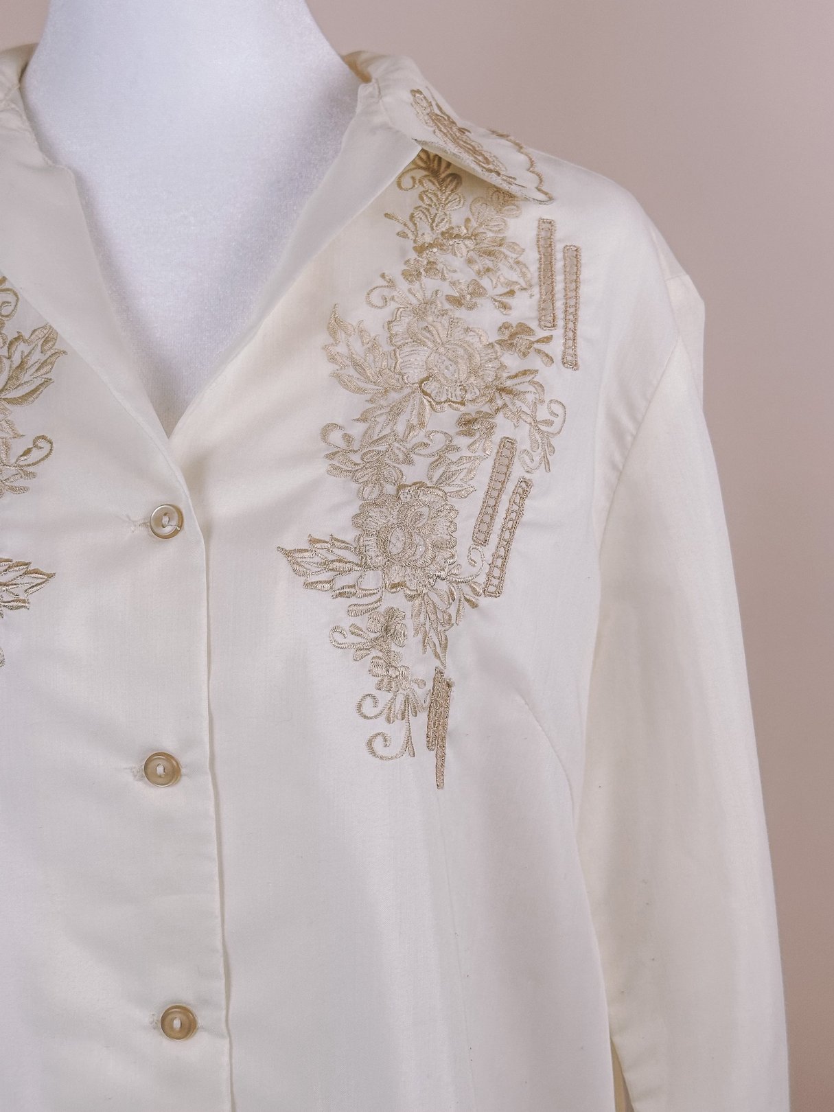 Cream hand-embroidered scalloped button-down blouse for women featuring floral designs in golden thread, reflecting a 1950s style.