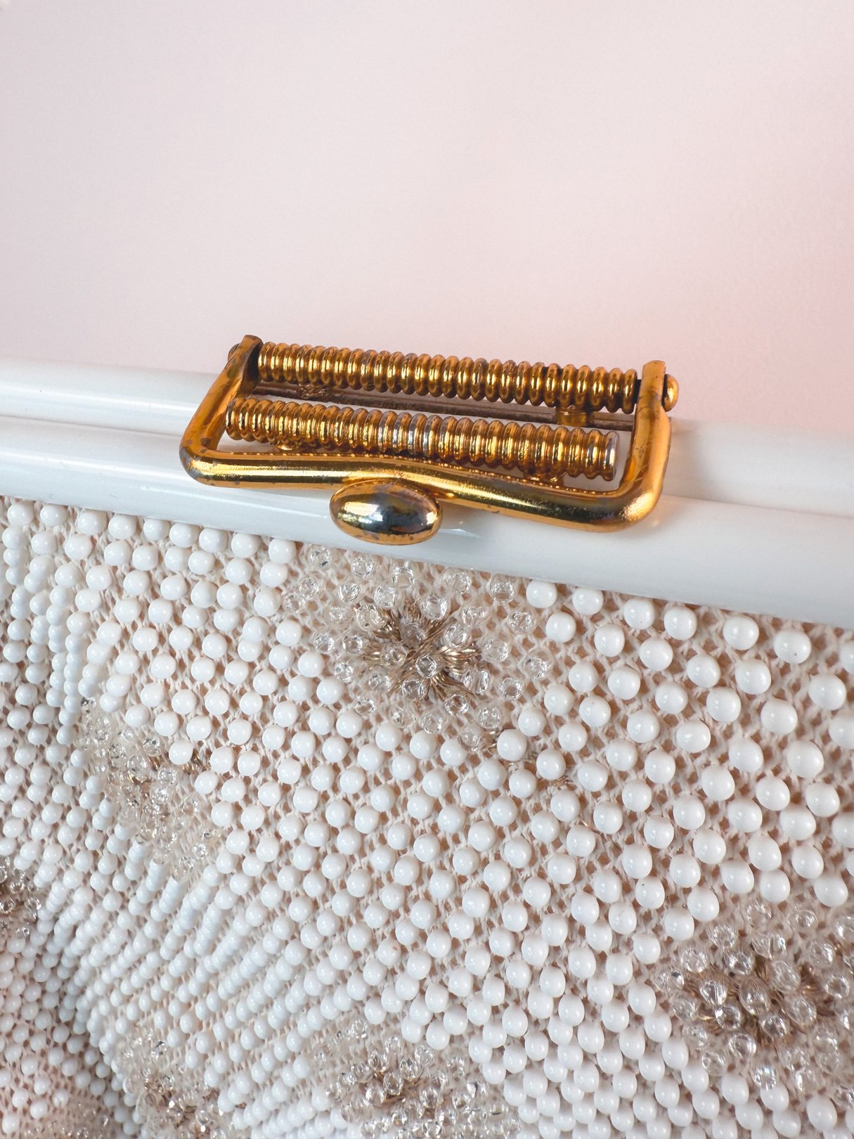 Cream white 1950s women's handbag featuring a beaded texture and a gold metallic clasp.