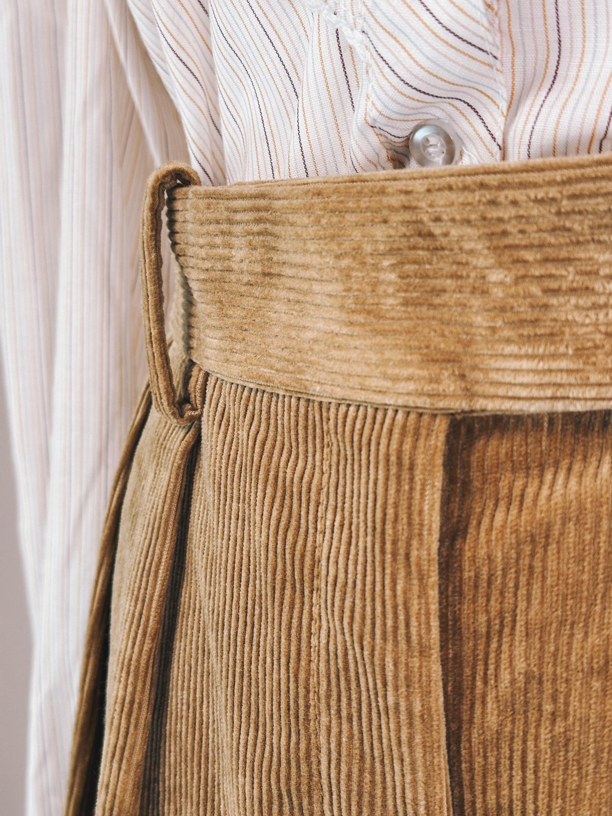 Toast brown corduroy pants for women, featuring a high waist and pleated details, inspired by the 1970s style.