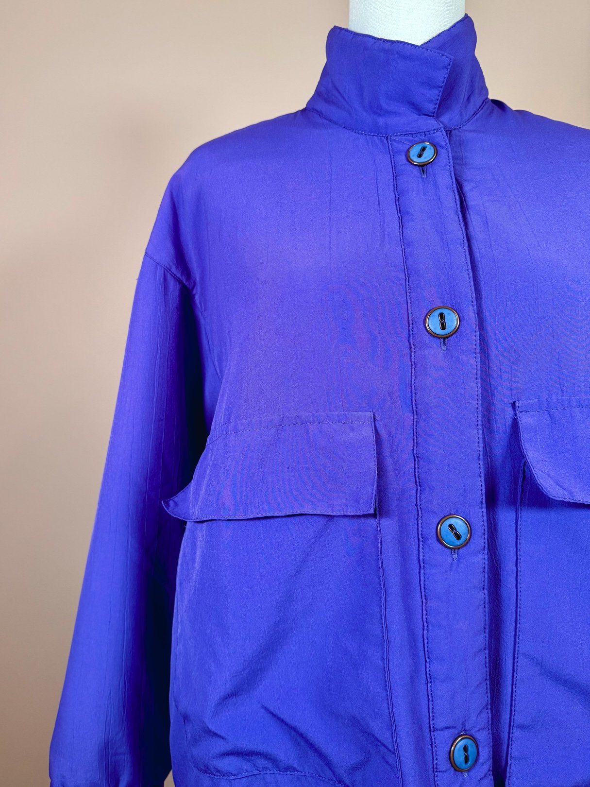 Vibrant violet women's jacket from the 1980s featuring a high collar and front pockets.